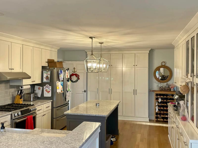 Modern kitchen interior with gray cabinets, stainless steel appliances, an island with a granite countertop painted by residential painters in Pittsburgh PA, and hardwood floors.